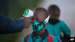 Un agent vérifiée la température d'un garçon en rapport avec pandémie de coronavirus, avant qu'il n'entre dans son école, à Johannesburg, en Afrique du Sud, le 7 juillet 2020.