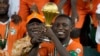 Ivory Coast captain Max-Alain Gradel and President Alassane Ouattara raise Africa Cup of Nations trophy after winning the final against Nigeria, at the Olympic Stadium of Ebimpe in Abidjan, February 11, 2024.