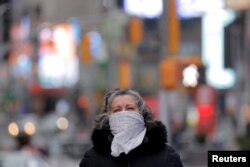 FILE - A woman walks in Times Square in New York City, May 9, 2020, as a polar vortex brought cold temperatures to the region. Cold and influenza viruses spread more easily in the winter in part because the air is drier.