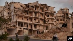 Motor cycles ride past buildings destroyed during the fighting in the northern town of Ariha, in Idlib province, Syria, Sept.20, 2018.