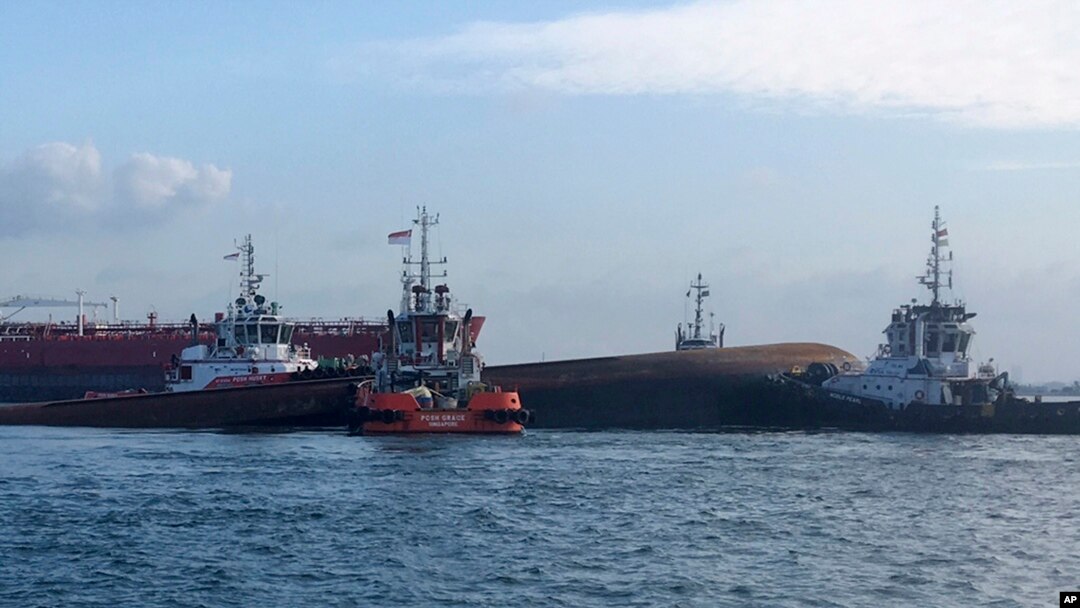 Empat kapal tunda (tug boats) menggerakkan kapal keruk yang sebagian tenggelam ke daerah dekat Pulau Senang, Singapura, dan menindaklanjuti operasi pencarian bawah air, Rabu, 13 September 2017. (Foto: Otoritas Maritim dan Pelabuhan Singapura via AP)