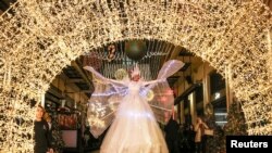 FILE - A performer dances in front of season decorations, in a shopping arcade in the centre of the city, ahead of the New Year's Eve celebrations in Athens, Greece, December 30, 2023.