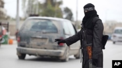 Similar to female fighters who run checkpoints for forces of Bashar al Assad in Damascus, a female member of the Al-Ikhlas [Loyalty] Battalion stops a van at a rebel checkpoint, Aleppo, March 31, 2013.