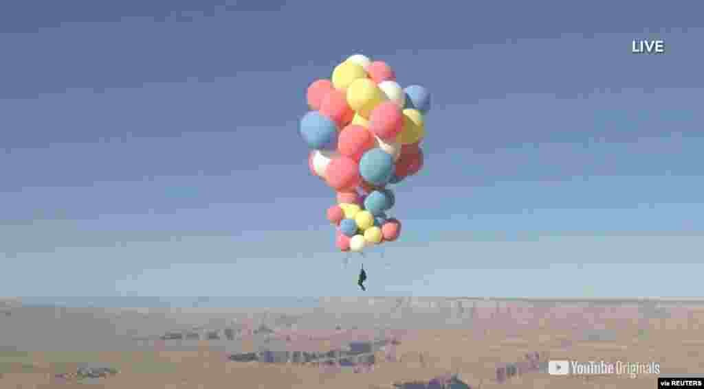 Extreme performer David Blaine hangs with a parachute under a cluster of balloons during a stunt to fly thousands of feet into the air, as shown in this still image from video, taken in Page, Arizona, Sept. 2, 2020. (David Blaine/Handout)