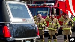 Bomberos saludan el paso del cortejo fúnebre de Daniel Gerard, de 7 años, una de las víctimas de la matanza en Connecticut, cuyo funeral se realizó ayer.