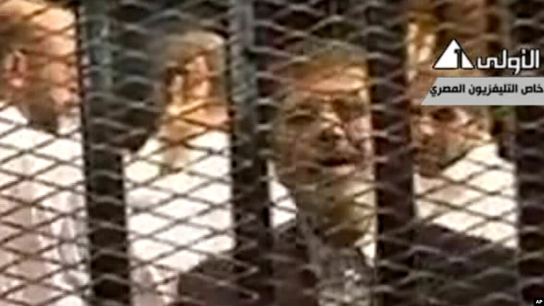 FILE - Video broadcast on Egyptian State Television shows ousted President Mohammed Morsi speaking from inside a mesh cage as he stands with other defendants during a court hearing at a police academy compound in Cairo, Egypt.