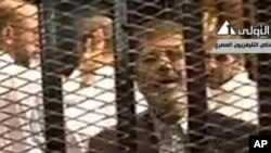 ရာထူးကဖြုတ်ချခံထားရတဲ့ အီဂျစ်သမ္မတဟောင်း မိုဟာမက် မော်စီကို ပထမအကြိမ် ရုံးထုတ်စစ်ဆေးချိန်မှာ အမှုတွဲများနဲ့အတူ တွေ့ရစဉ်။ (နိုဝင်ဘာ ၄၊ ၂၀၁၃) 