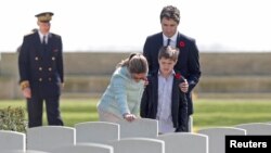 Canadian Prime Minister Justin Trudeau, his wife Sophie Gregoire and son Xavier pay their respects at the tombstone of J.R. Gregoire, an ancestor who died during fighting in WWII, during their visit to the Canadian War Cemetery in Beny-sur-Mer, France, April 10, 2017.