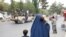 An Afghan woman walks with her children on the anniversary of the fall of Kabul on a street in Kabul