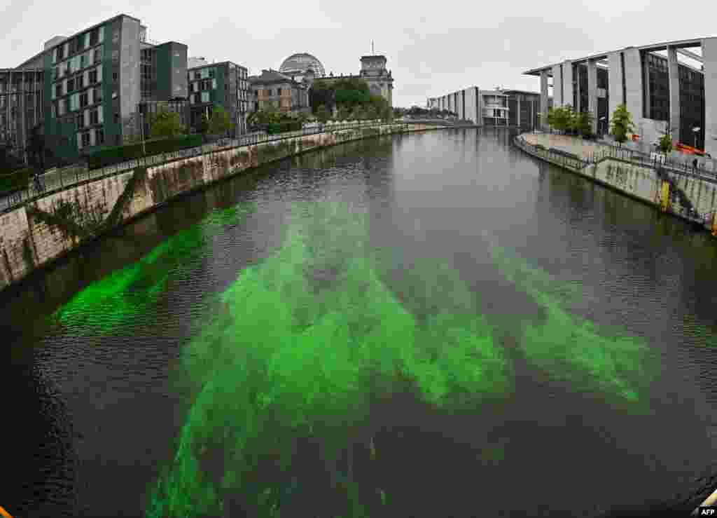 A section of the River Spree next to the Reichstag building, seat of the German lower house of Parliament Bundestag, is colored green by activists from the "Extinction Rebellion" to protest the government's coal policies in Berlin.