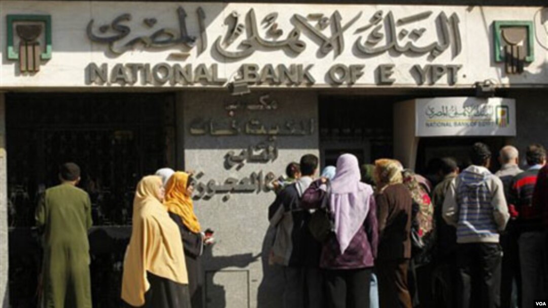 Warga di Mesir mengantri untuk mengambil uang dari bank. Bank-bank di Kairo buka selama beberapa jam, Minggu (2/5).