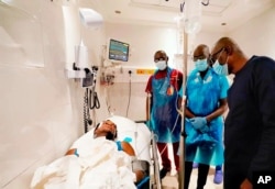 In this photo released by the Lagos State government press, governor Babajide Sanwo-Olu, right, visit victims injured in last night's protests in a hospital in Lagos, Nigeria, Oct. 21, 2020.