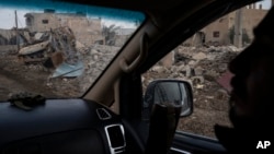 A U.S.-backed Syrian Democratic Forces (SDF) fighter rides past destroyed homes and vehicles in a village recently retaken from Islamic State militants in Susah, Syria, Feb. 16, 2019.