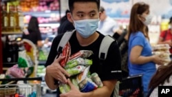 A man wearing a protective mask looks for the start of the queue at a grocery store in Taguig, metropolitan Manila, Philippines on Friday, March 13, 2020. Many people trooped to supermarkets and stocked up on supplies as the Philippine president announced