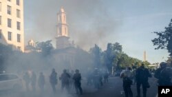 Gases lacrimógenos flotan en el aire mientras un grupo de policías aleja a los manifestantes de la Iglesia de San Juan al otro lado del Parque Lafayette, frente a la Casa Blanca, durante protestas por la muerte de George Floyd, el 1 de junio de 2020.