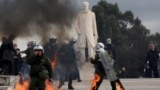 Riot police walk with their gear on fire, after being struck by Molotov cocktails at a protest near the Greek parliament, marking the second anniversary of the country's worst railway disaster, in Athens, Greece, Feb. 28, 2025. 