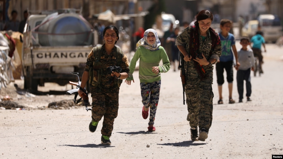 Pripadnice Sirijskih demokratskih snaga (SDF) trče tokom igre sa decom u gradu Tabka, Sirija, nakon zauzimanja grada od militanata ISlamske države, 12. maja 2017. (Rojters)