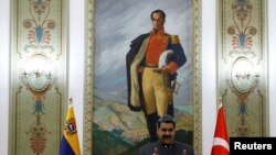 El presidente de Venezuela, entre sendas banderas, venezolana y turca, durante una recepción al ministro de Exteriores de Turquía, Mevlut Cavusoglu, en el palacio de Miraflores, en Caracas, el 29 de abril de 2022.