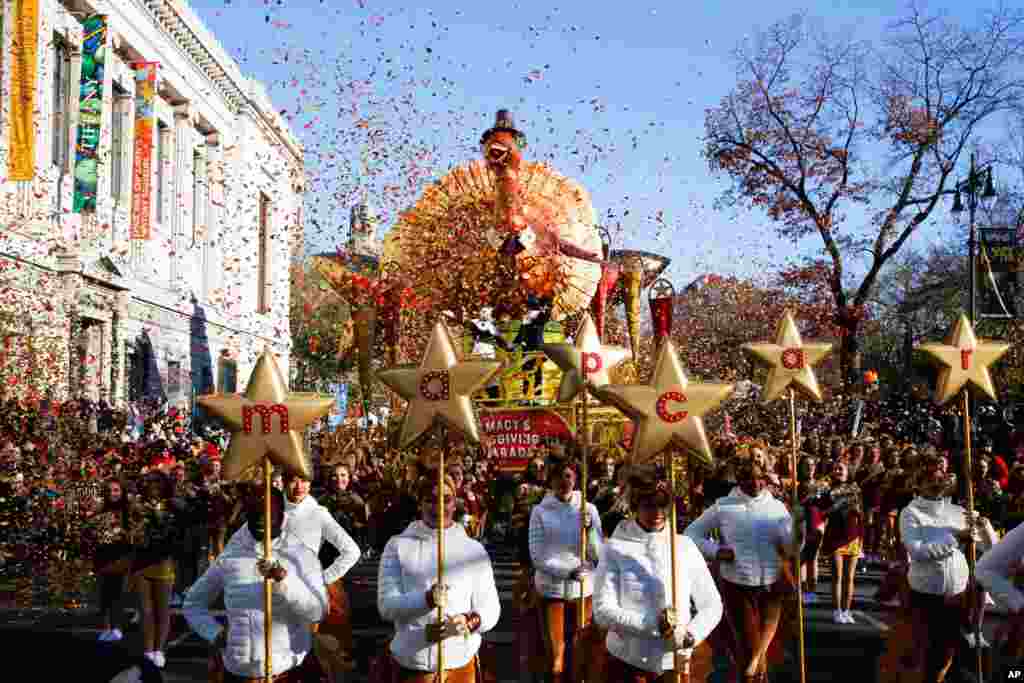 Los artistas caminan frente al flotador Tom Turkey de Macy&#39;s, mientras participan en el desfile. 