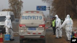 Para pekerja menyemprotkan cairan disinfektan ke kendaraan yang melintas setelah wabah flu babi merebak di pinggiran Kota Beijing, China, 23 November 2018.