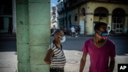 People wearing masks due to the new coronavirus pandemic stand near an area that was gated off to help contain the spread of COVID-19 in Havana, Cuba, Feb. 22, 2021. 