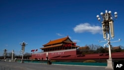 A masked paramilitary policeman stands guard at a deserted Tiananmen Gate following the coronavirus outbreak, in Beijing, Feb. 16, 2020. China said Monday it may postpone its annual congress in March, its biggest political meeting of the year.