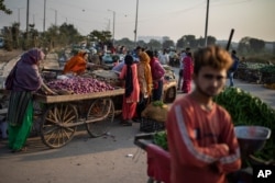FILE - Vendors and customers are seen without masks at a market on the outskirts of New Delhi, India, Nov. 20, 2020.