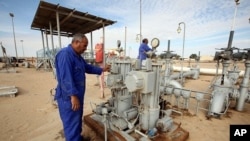 Workers check pipes and valves at Amaal oil field in eastern Libya, October 7, 2011.