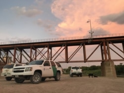 U.S. Border Patrol agents await a detainee transfer under a train bridge in Laredo, Texas, Aug. 6, 2019. (V. Macchi/VOA)