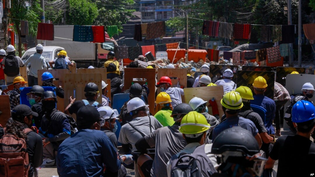 Pengunjuk rasa anti-kudeta berlindung untuk mencegah personel keamanan masuk selama demonstrasi di Yangon, Myanmar Kamis, 4 Maret 2021. (Foto: AP)