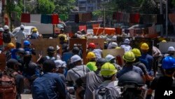 Pengunjuk rasa anti-kudeta berlindung untuk mencegah personel keamanan masuk selama demonstrasi di Yangon, Myanmar Kamis, 4 Maret 2021. (Foto: AP)