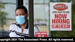 FILE - A "Now Hiring" sign is seen as a customer leaves a restaurant in Mayfield Heights, Ohio, June 4, 2021. Hiring in the U.S. has picked up with many companies struggling to find enough workers to keep up with the economy's swift recovery.