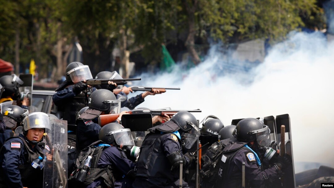 在曼谷政府大厦附近发生的冲突中，泰国防暴警察把武器对准反政府示威者。（2014年2月18日）