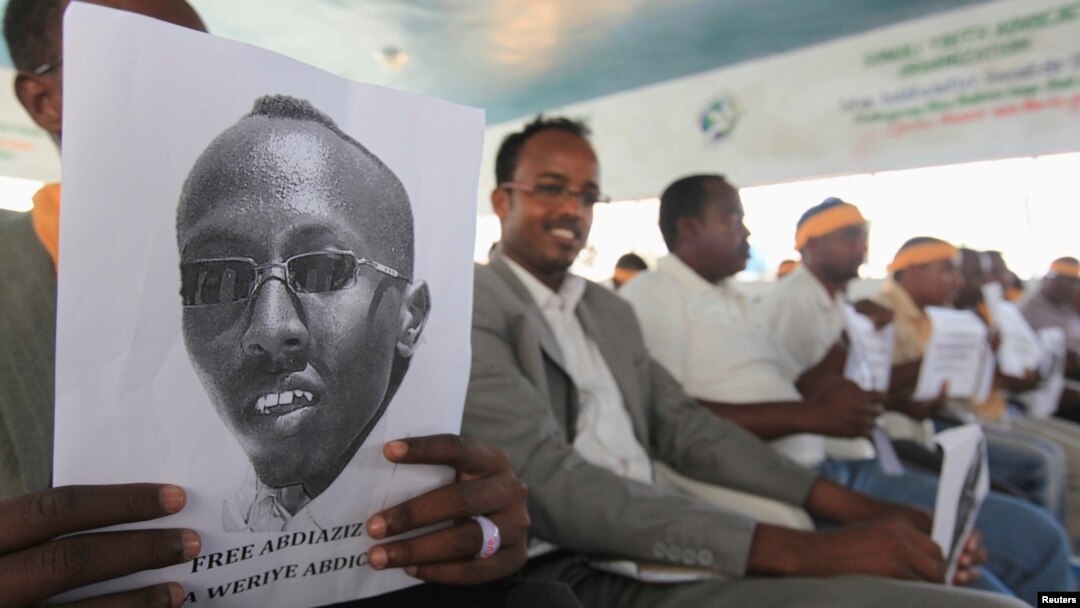 Somali jurnalistlari hibsga olingan hamkasbi suratini ushlab turibdi. 27-yanvar 2013-yil. 