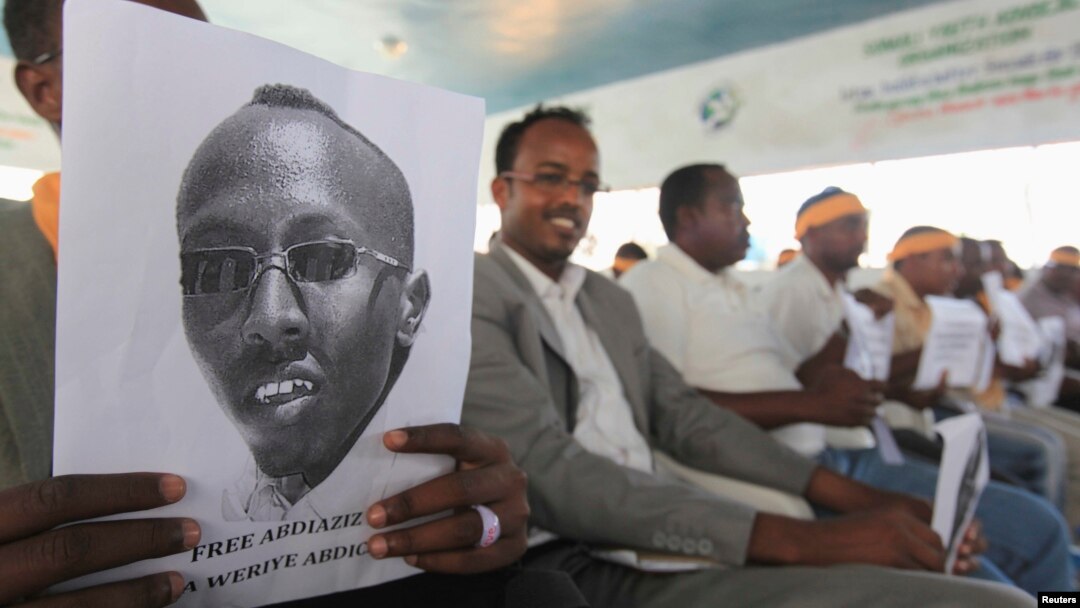 A Somali journalist holds a poster bearing the image of Abdiaziz Abdinur in Mogadishu in this January 27, 2013, file photo..