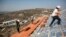 FILE - Men work on the roof of a house under construction in the unauthorized Jewish settler outpost of Havat Gilad, south of the West Bank city of Nablus, Nov. 2013. 