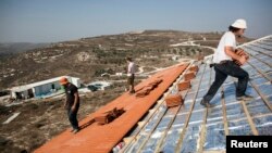 FILE - Men work on the roof of a house under construction in the unauthorized Jewish settler outpost of Havat Gilad, south of the West Bank city of Nablus, Nov. 5, 2013.