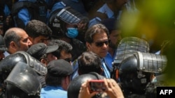 FILE - Police officers escort Pakistan's former Prime Minister Imran Khan, center, upon his arrival at the High Court in Islamabad, May 12, 2023.