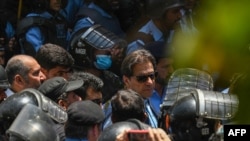 FILE - Police escort Pakistan's former Prime Minister Imran Khan upon his arrival at the high court in Islamabad on May 12, 2023.