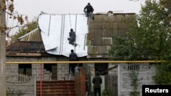 People fix the roof of a house, damaged in fighting between Ukrainian troops and rebels, in the Oktyabrsky district of Donetsk, Ukraine, Oct. 25, 2017.