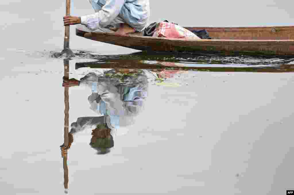 A Kashmiri fisherman rows a boat after a rainfall in Srinagar.