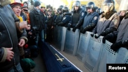 Interior Ministry officers stand guard as European integration supporters hold a rally, with a symbolic coffin seen in the middle, near the residence of Ukraine's President Viktor Yanukovych, outside Kyiv, Dec. 29, 2013.