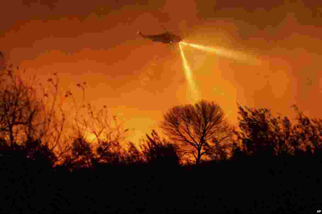 A helicopter drops water while fighting the Auto Fire in Ventura County, California, Jan. 13, 2025. 