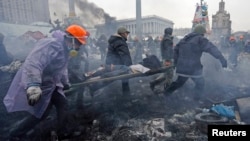 Manifestantes antigubernamentales cargan a un herido luego de enfrentamientos con policías antimotines en la Plaza de la Independencia, en Kiev.