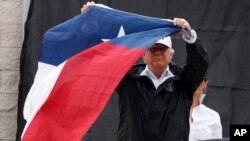 President Donald Trump holds up a Texas flag after speaking with supporters outside Firehouse 5 in Corpus Christi, Texas, Aug. 29, 2017, where he received a briefing on Harvey relief efforts.