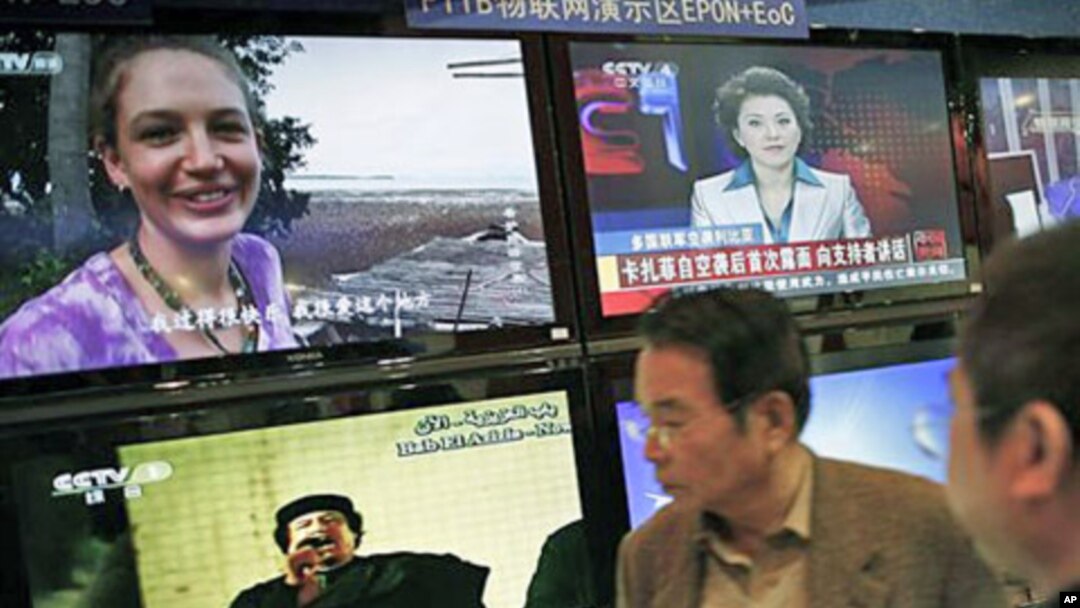 Visitors watch TV screens broadcasting news of Libyan leader Moammar Gadhafi speaking to his supporters, bottom left, during the China Content Broadcasting Network Expo in Beijing, March 23, 2011 (file photo)