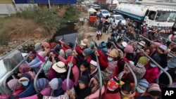 Cambodian garment factory workers ride on the back of a truck as they head to their homes at the evening traffic jump of Sre Cheah village outside Phnom Penh, Cambodia, Saturday, Jan. 11, 2020. (AP Photo/Heng Sinith)