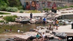 Orang-orang mendinginkan diri suatu sungai di Denver, Rabu 16 Juni 2021. Gelombang panas terus melanda AS bagian barat, mendorong suhu hingga 99 derajat di Denver. (Foto: AP/Brittany P)