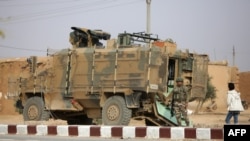 FILE - A Turkish soldier stands near his armored vehicle on a highway near the northern Syrian town of Ain Issa in the countryside of the Raqqa region, Nov. 26, 2019, as Turkey-backed forces were deploying reinforcements around town.