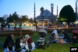 Umat Muslim berbagi hidangan buka puasa pada hari pertama Ramadan di Alun-alun Sultanahmet, dengan latar belakang Masjid Biru di Istanbul, Turki, 1 Maret 2025. (Yasin AKGUL/AFP)